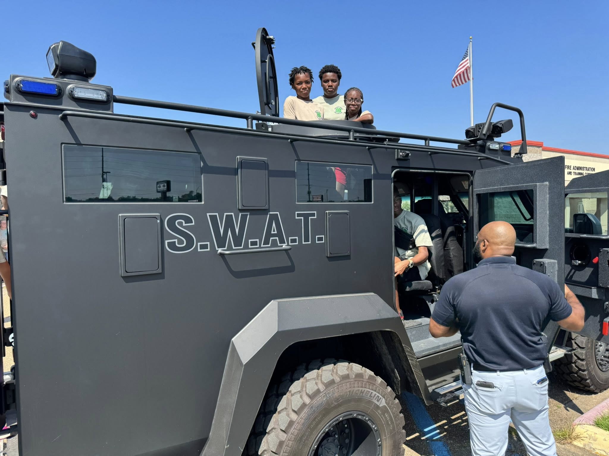 Three kids poking their heads out the top of a S.W.A.T. vehicle.
